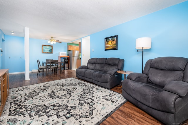 living room featuring dark hardwood / wood-style flooring, a textured ceiling, and ceiling fan