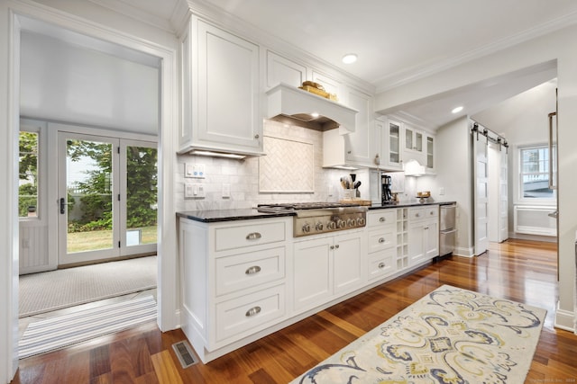 kitchen with stainless steel gas stovetop, a barn door, and white cabinets