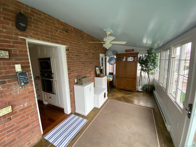 unfurnished sunroom featuring vaulted ceiling, a baseboard heating unit, and ceiling fan