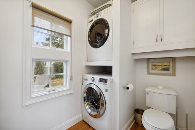 laundry area featuring light wood-type flooring and stacked washer / dryer