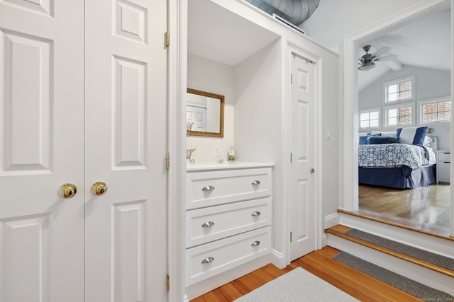 interior space with vanity, ceiling fan, vaulted ceiling, and wood-type flooring