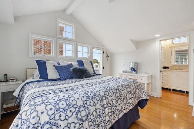 bedroom featuring light wood-type flooring, lofted ceiling with beams, and ensuite bathroom