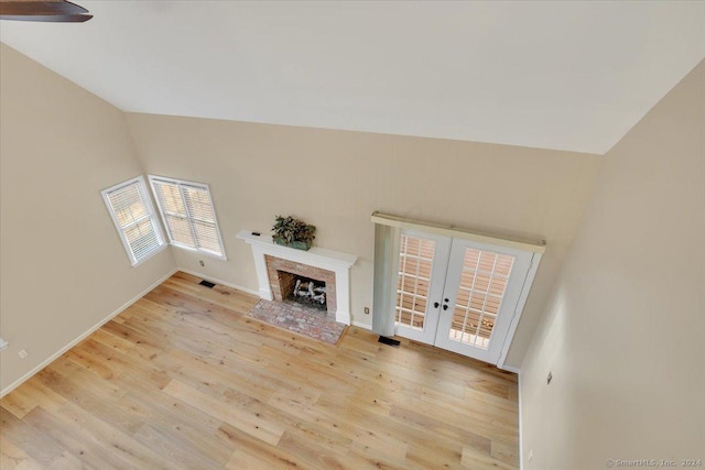 unfurnished living room with french doors, lofted ceiling, and light wood-type flooring