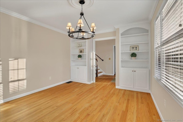 empty room featuring ornamental molding, light hardwood / wood-style floors, built in features, and a notable chandelier