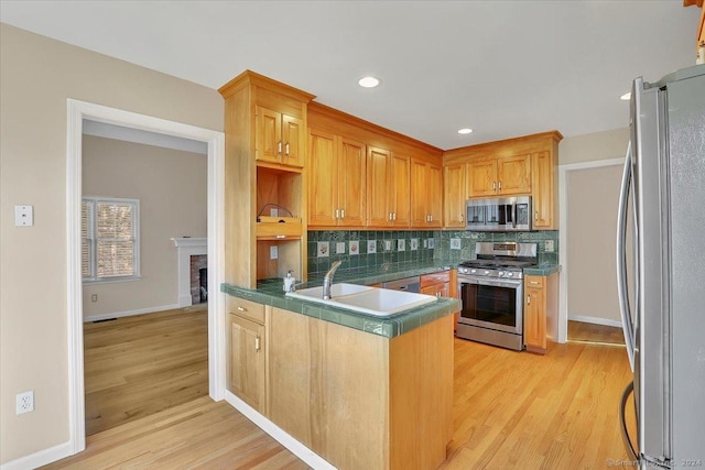 kitchen featuring decorative backsplash, sink, appliances with stainless steel finishes, and light hardwood / wood-style flooring