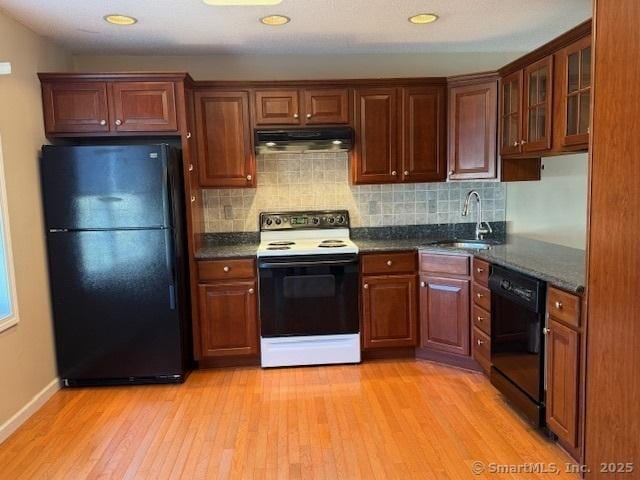 kitchen with sink, dark stone counters, decorative backsplash, black appliances, and light wood-type flooring