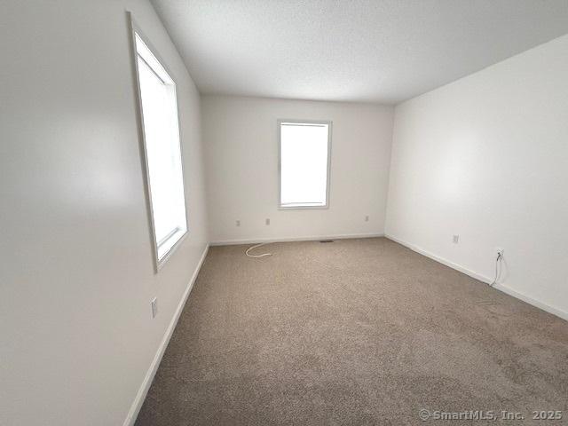 spare room featuring carpet floors and a textured ceiling