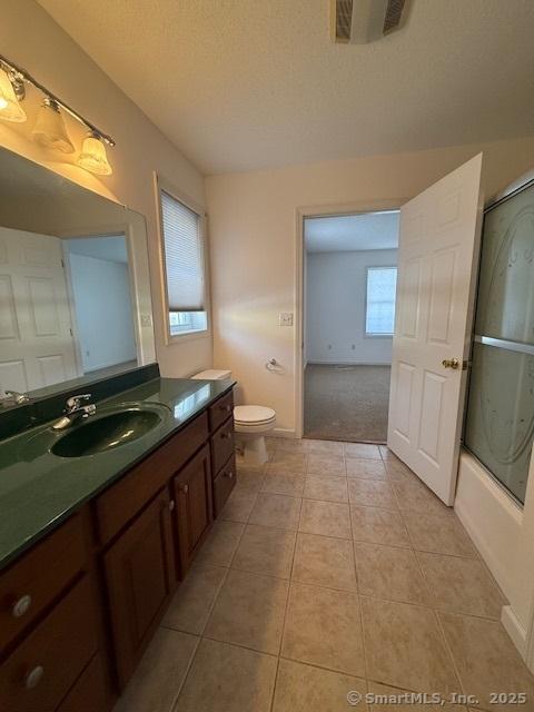 full bathroom featuring toilet, shower / bath combination with glass door, a textured ceiling, vanity, and tile patterned flooring