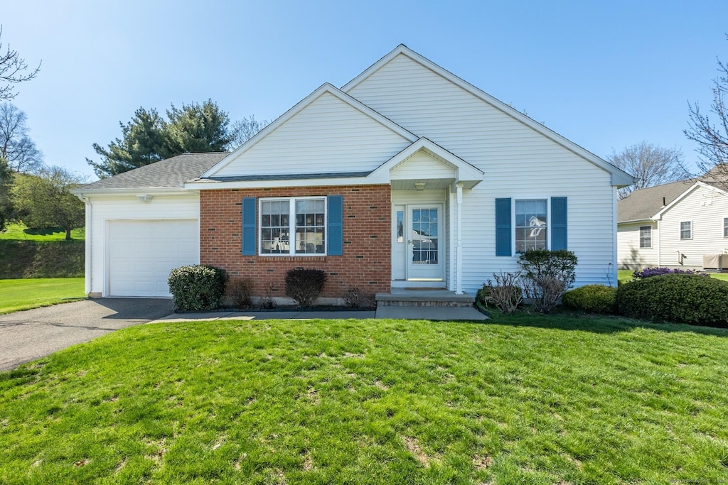 view of front facade with aphalt driveway, brick siding, a front yard, and a garage