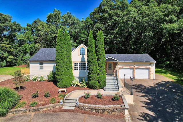 view of front facade featuring stairs, roof with shingles, concrete driveway, and an attached garage