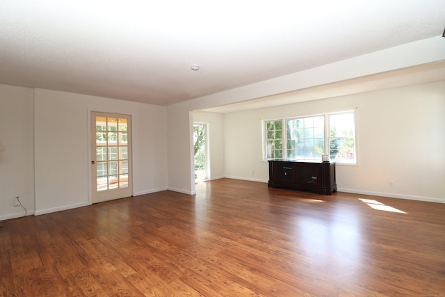 spare room with a healthy amount of sunlight, baseboards, and wood finished floors