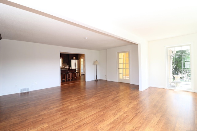 spare room with light wood finished floors, visible vents, and baseboards