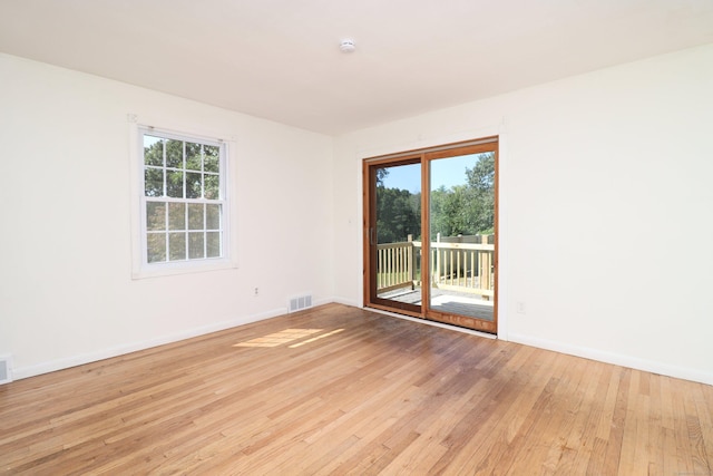 unfurnished room with baseboards, light wood-type flooring, and a wealth of natural light