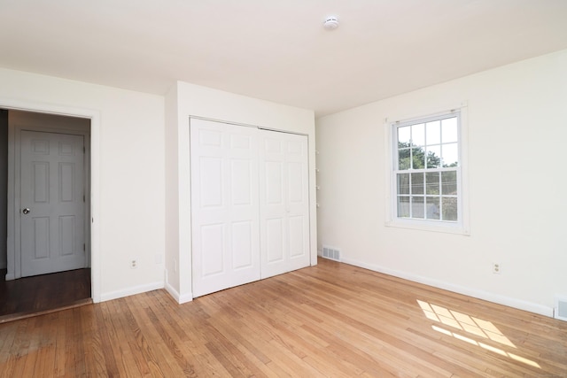 unfurnished bedroom featuring visible vents, baseboards, a closet, and light wood finished floors