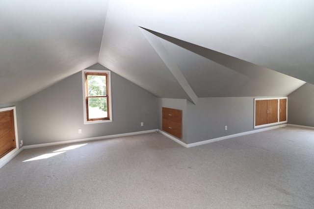 bonus room with lofted ceiling, baseboards, and light carpet