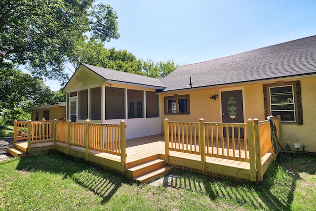 rear view of house featuring a sunroom, a yard, roof with shingles, and a wooden deck