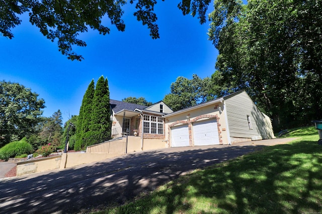 view of front of home featuring aphalt driveway, an attached garage, and a front lawn