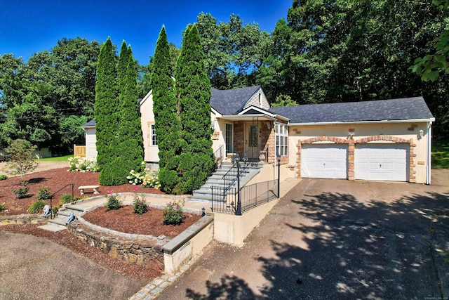 view of front of home with aphalt driveway, stone siding, a garage, and stucco siding