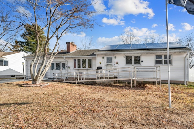 back of house featuring a lawn and solar panels