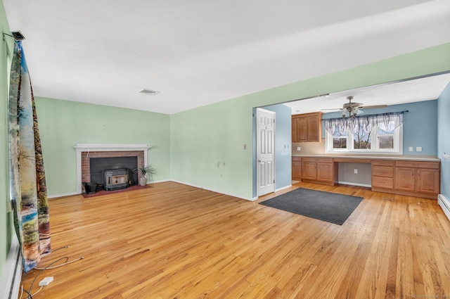 unfurnished living room with ceiling fan, built in desk, and light hardwood / wood-style floors