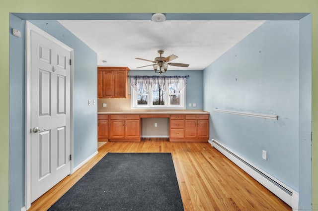 kitchen featuring light hardwood / wood-style flooring, ceiling fan, built in desk, decorative backsplash, and a baseboard radiator