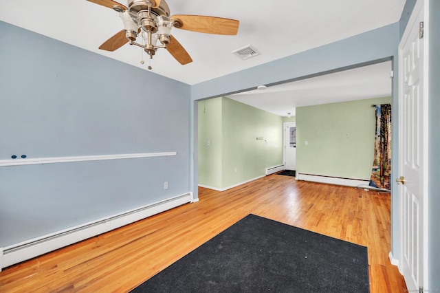 spare room featuring baseboard heating and wood-type flooring