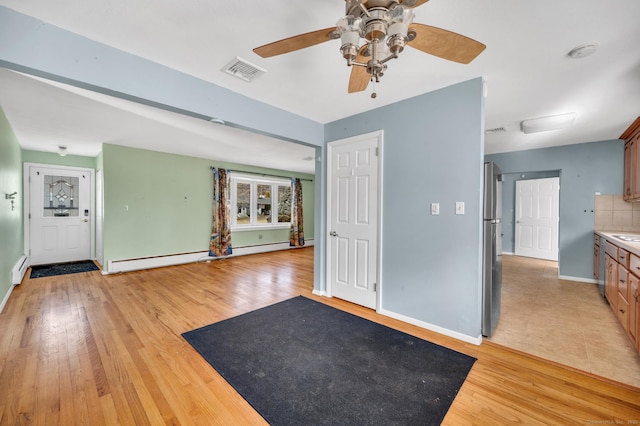 interior space with ceiling fan, baseboard heating, and light wood-type flooring