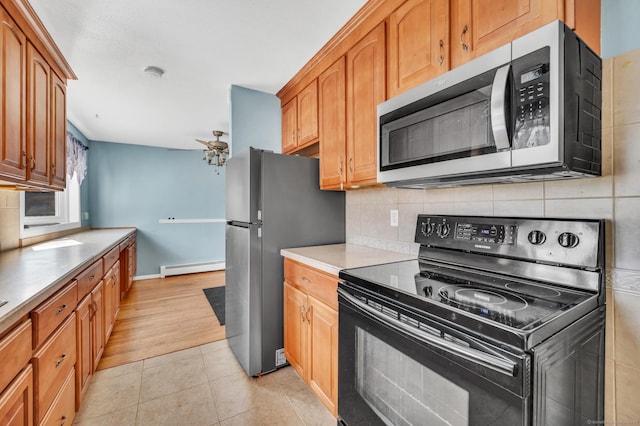 kitchen with baseboard heating, appliances with stainless steel finishes, light tile patterned flooring, and backsplash