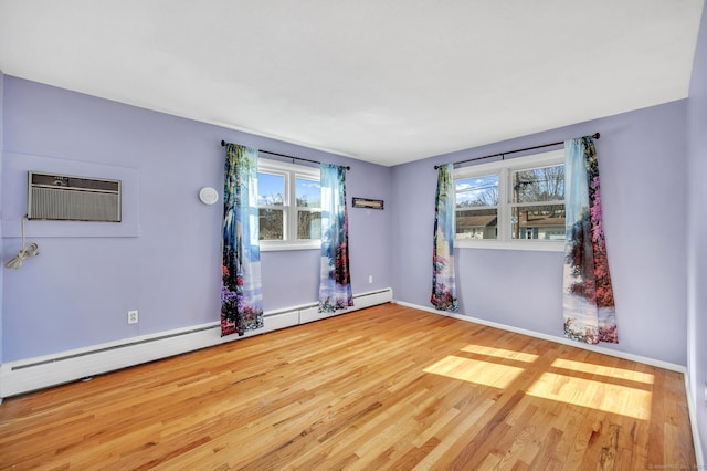 spare room featuring an AC wall unit, light hardwood / wood-style floors, and a baseboard heating unit