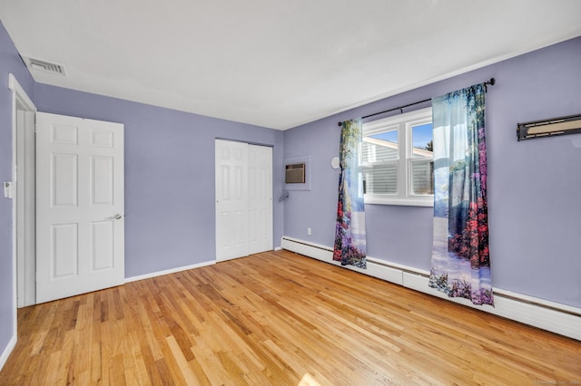 unfurnished room featuring a baseboard radiator and light hardwood / wood-style floors