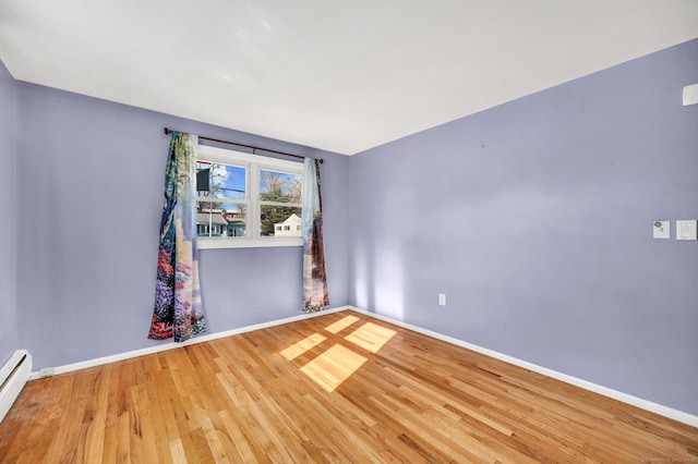 empty room with wood-type flooring and baseboard heating