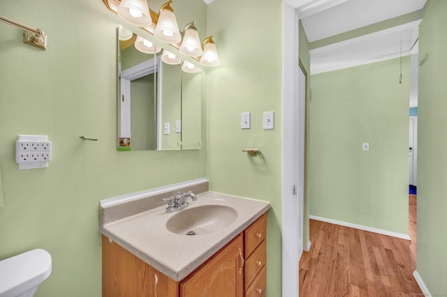 bathroom with vanity, a notable chandelier, wood-type flooring, and toilet