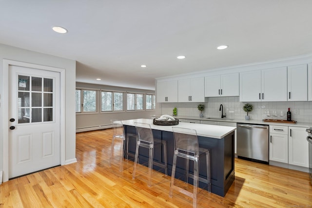 kitchen with dishwasher, white cabinetry, a kitchen island, and sink