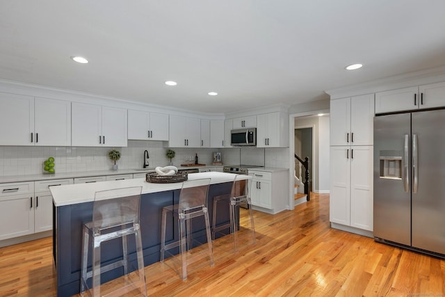 kitchen featuring decorative backsplash, stainless steel appliances, sink, white cabinets, and a kitchen island