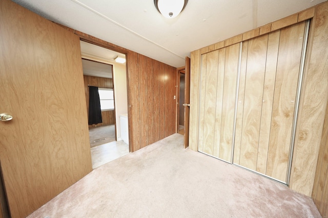 interior space with wood walls, a closet, and light colored carpet