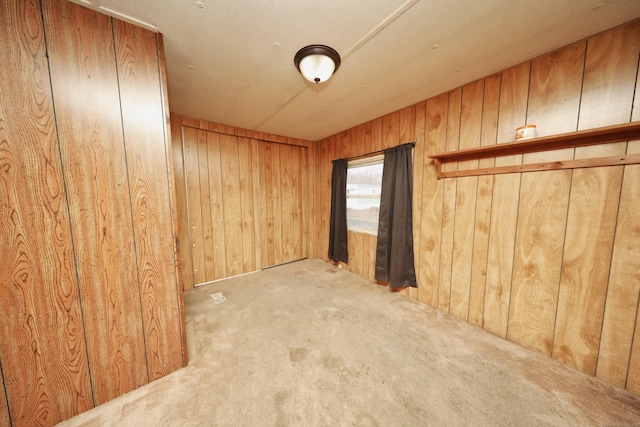 carpeted empty room with wood walls