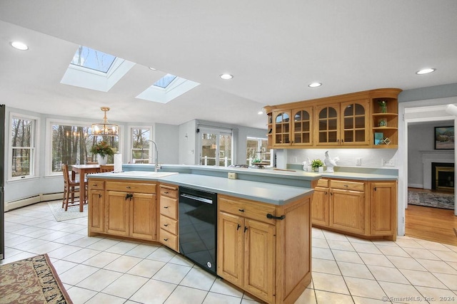 kitchen featuring dishwasher, a notable chandelier, an island with sink, pendant lighting, and vaulted ceiling with skylight