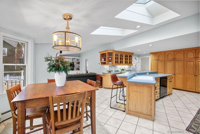 kitchen with a skylight, sink, a chandelier, decorative light fixtures, and a center island with sink