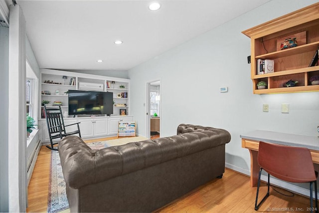 living room featuring built in features, light hardwood / wood-style flooring, a baseboard radiator, and vaulted ceiling