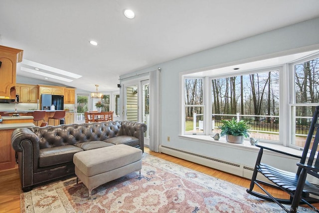 living room featuring vaulted ceiling with skylight and light hardwood / wood-style floors