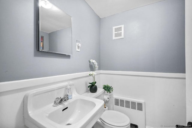 bathroom featuring toilet, radiator heating unit, and sink