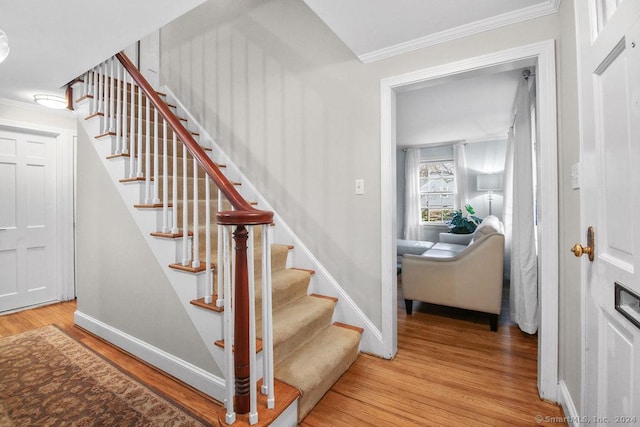 stairs with crown molding and wood-type flooring