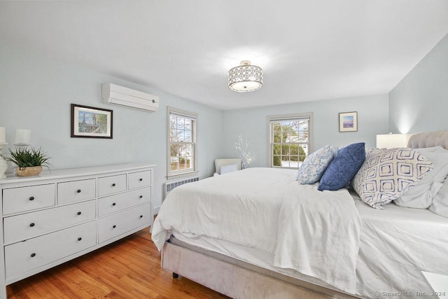 bedroom with a wall mounted air conditioner, multiple windows, radiator, and light hardwood / wood-style flooring