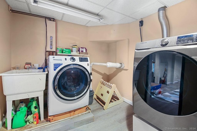 laundry room with washer and dryer, wood-type flooring, and sink