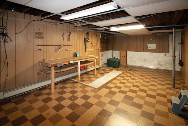 basement featuring a baseboard radiator and wooden walls