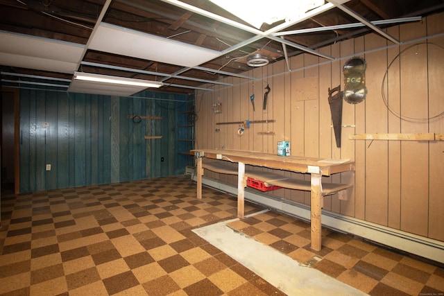 basement featuring a workshop area, baseboard heating, and wood walls