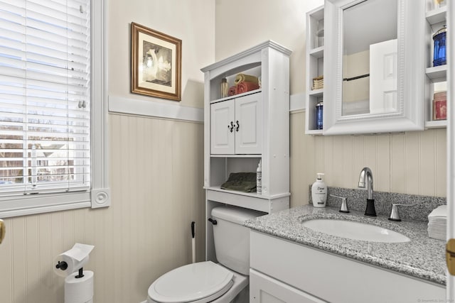 bathroom with vanity, toilet, and wooden walls