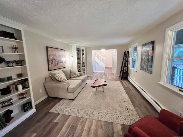 living room with built in shelves, a baseboard radiator, and a textured ceiling