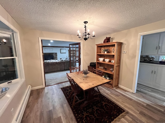 dining area with a textured ceiling, dark hardwood / wood-style flooring, a baseboard radiator, and a notable chandelier