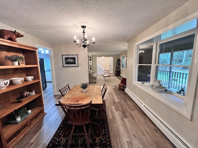 dining room with dark wood-type flooring, a baseboard radiator, a textured ceiling, and an inviting chandelier